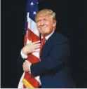  ??  ?? Trump hugs a US flag as he comes onstage at a rally in Tampa, Florida.