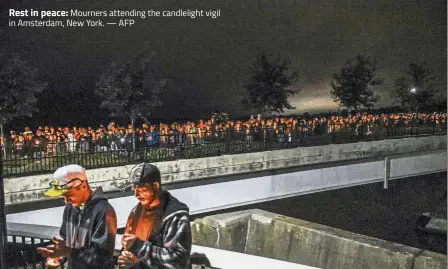  ?? — AFP ?? Rest in peace: Mourners attending the candleligh­t vigil in Amsterdam, New York.