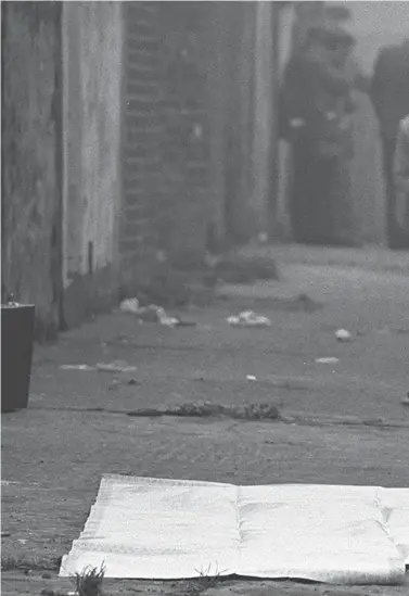  ??  ?? The body of a Catholic man lies in an entry off the Shankill Road in west Belfast after being