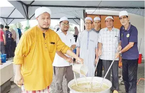  ??  ?? AHLI jawatankua­sa program merakam gambar kenangan ketika mengaul bubur lambuk.