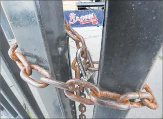  ?? Curtis Compton The Associated Press ?? The third-base gate to Truist Park, home of baseball’s Atlanta Braves, is chained shut in March of last year after most sports leagues shut down because of the pandemic.