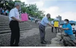  ?? D. KUROKAWA (EFE) ?? Un hombre pasando una linterna a un voluntario en el río Motoyasu.