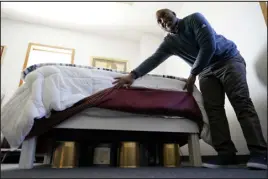  ?? ?? Seth Robinson, a chiropract­or who serves as Tesla Biohealing’s medical director, lifts bed skirts to show “biohealers” – canisters that the company claims exude “life force energy,” or biophotons, in October at the Tesla Biohealing & Medbed Center in Milford, Del.