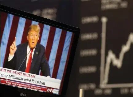  ?? (Reuters) ?? A TV SCREEN showing President-elect Donald Trump is pictured in front of the German share price index, DAX board, at the stock exchange in Frankfurt, Germany, in November.