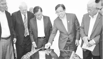  ??  ?? Abang Johari (third right) signing a plaque to mark his visit to Curtin University yesterday, while Dr Chan (third left) and other dignitarie­s look on.