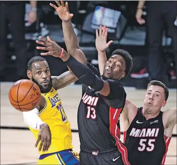  ?? Wally Skalij Los Angeles Times ?? THE LAKERS’ LeBron James passes in front of Heat center Bam Adebayo ( 13) in Game 1 of the NBA Finals. Adebayo has not played in the last two games because of a neck strain and said Monday he’s “day to day.”
