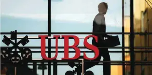  ?? — Reuters ?? A man is seen walking behind UBS logo in Zurich, Switzerlan­d.