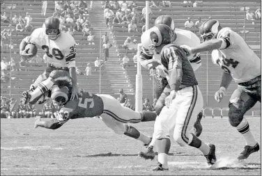  ?? Associated Press ?? Legend dies: Minnesota Vikings halfback Hugh McElhenny, left, takes to the air to get past a Los Angeles Rams tackler during an NFL football game in Los Angeles, on Oct. 21, 1962. McElhenny, an elusive NFL running back nicknamed “The King,” died on June 17, 2022, at his home in Nevada, his son-in-law Chris Permann confirmed Thursday. He was 93.