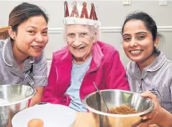  ??  ?? Care assistants Diya Gurung and Amandeep Kaur and resident Doreen Mainwaring make a cake for the royal party at Franklin Hous Photo credit : Simon Jacobs