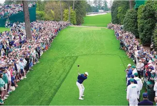  ?? JAE C. HONG/ASSOCIATED PRESS ?? Tiger Woods hits from the 18th tee during a practice round on Monday at Augusta National, with fans lining the fairway. Woods is scheduled to play this week in the Masters, a tournament he has won five times.