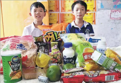  ?? PROVIDED TO CHINA DAILY ?? Yuan Jinghao and Zhu Xinyu, two cousins born in 2008 and 2009, proudly pose together with their snacks. However, the daily amount of snacks they are allowed to take is limited.