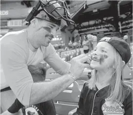  ?? KARL MERTON FERRON/BALTIMORE SUN ?? Johnny Utah of Baltimore puts eye black on his daughter, Juli, 6, before the Orioles home opener against the Red Sox at Camden Yards.