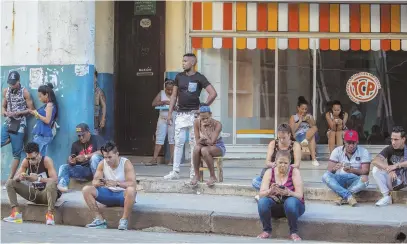  ?? AP PHOTOS ?? CATCHING UP: People use a public Wi-Fi hotspot in Havana, above, while home internet has just come to Cuba in a limited pilot program. Havana resident Yolanda Mollinedo, below left, looks at her granddaugh­ter Alejandra in Virginia on her smartphone...