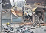  ?? SANCHIT KHANNA/HT ?? A security person walks past burnt shops in northeast Delhi after riots broke out in February last year.