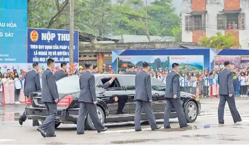  ?? — AFP photo ?? Kim (centre) waves from inside his car surrounded by bodygurads as he leaves the Dong Dang railway station in Dong Dang, Lang Son province.