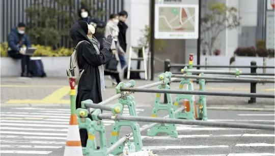  ?? The Yomiuri Shimbun ?? A woman joins her hands in mourning on Sunday as she looks up from the site where former Prime Minister Shinzo Abe was shot dead in Nara on July 8.