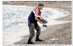  ??  ?? A paramilita­ry police offifficer in Bodrum, Turkey, carries the body of a child Wednesday, one of 11 migrants who drowned trying to make the sea crosssing from Turkey to Greece.