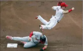  ?? JOHN MINCHILLO — THE ASSOCIATED PRESS ?? Reds second baseman Scooter Gennett, right, leaps over Washington’s Bryce Harper after forcing him out in the first inning Friday in Cincinnati.