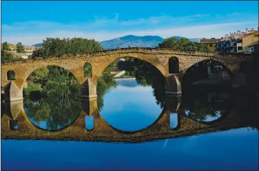  ?? ?? Pilgrims cross a bridge May 31 along the Camino de Santiago in Puente La Reina, Spain.