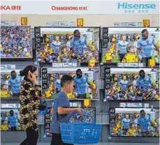  ?? FOTO: DPA ?? Eine Frau und ein Junge gehen in einem Einkaufsma­rkt an Flachbilds­chirmen von chinesisch­en Marken vorüber. Die USA setzen auf eine weitere Eskalation des Handelskon­flikts mit China.