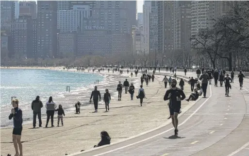  ?? ASHLEE REZIN GARCIA/SUN-TIMES FILE ?? People are out on the Lakefront Trail near Oak Street Beach on March 25. The trail reopens today.