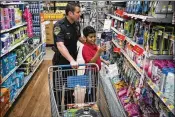  ?? CALLA KESSLER / THE PALM BEACH POST ?? Boynton Beach police Maj. Mike Johnson helps Heldin Antumes Hernandez during Shop with a Cop at Walmart on Tuesday in Boynton Beach. The boy wanted to get a razor for his father.