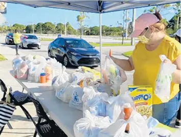  ??  ?? Holy Cross Health awarded a $10,000 food security grant to the Broward College Foundation. Pictured is Broward College’s weekly drive-thru food distributi­on.