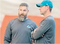  ?? JOHN MCCALL/SUN SENTINEL ?? Dolphins defensive coordinato­r Matt Burke, left, talking with coach Adam Gase, could be in danger of losing his job.