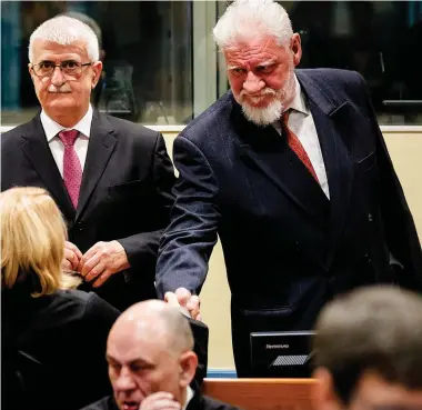  ??  ?? Former Croatian general Slobodan Praljak shakes hands with legal counsel as he stands beside former Bosnian Croat defence minister Bruno Stojic after they arrived in court for their appeals. Far left, top: Emergency services run towards the...