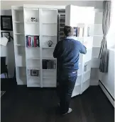  ??  JOHN LUCAS/POSTMEDIA NEWS ?? Colin Waugh opens the bookshelve­s along one wall in his loft condo. In 10 seconds he’ll have the wall bed behind them pulled out.