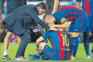  ?? FOTO: P. PUNTÍ ?? Messi cae lesionado durante el partido Barça-Atlético, mientas el Doctor Pruna e Iniesta lo atienden