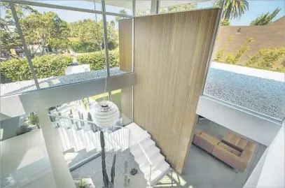  ??  ?? A 1957 INDUSTRIAL pendant light by Poul Henningsen hangs above a steel staircase and indoor succulent garden.