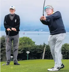  ??  ?? Liam Cahill looks on as Michael O’hanlon, wearing a protective visor, plays at Howth Golf Club in Dublin. Right, Alan O’sullivan at the same course