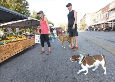 ?? NWA Democrat-Gazette/FLIP PUTTHOFF ?? Tara and Mark Kinsley shop Sept. 16 with their dogs Buster (left) and Peter at the Bentonvill­e Farmers Market. Northwest Arkansas businesses see steady traffic of customers with dogs on Saturday during farmers market hours.