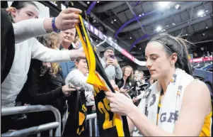  ?? Nam Y. Huh The Associated Press ?? Iowa guard Caitlin Clark autographs a fan’s jersey Wednesday after the No. 3 Hawkeyes beat Northweste­rn 110-74 at Welsh-ryan Arena.