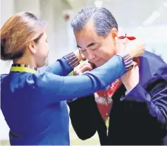  ??  ?? Wang receives a lei from an usherette upon arrival at the internatio­nal airport of Pasay to attend the 50th Asean Foreign Ministers meeting. — Reuters photo