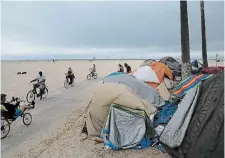  ?? JAE C. HONG THE ASSOCIATED PRESS FILE PHOTO ?? People ride their bikes past a homeless encampment set up along the boardwalk in the Venice neighbourh­ood of Los Angeles.