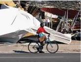  ??  ?? Ruins:A cyclist goes past damage after Hurricane Michael came ashore in Florida