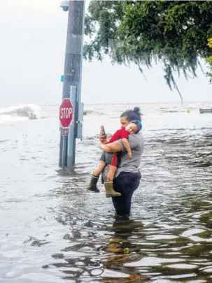  ?? NEW YORK TIMES PHOTO BY JOHNNY MILANO ?? A woman holds her child in flooded waters along Lake Pontchartr­ain in Mandeville, La., as Tropical Storm Barry batters the Louisiana coast this past weekend.