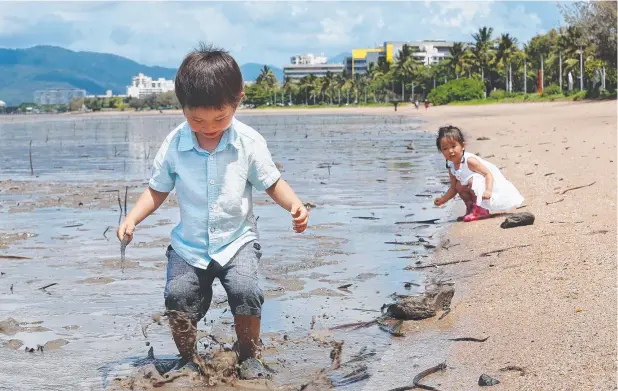  ?? Picture: BRENDAN RADKE ?? MUDDY MARVELLOUS: Hugo Orland, 3, splashes in the mud at low tide on the Cairns Esplanade as Yui Saito, 2, watches on.