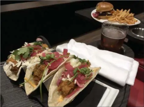  ?? PHOTOS BY MARK MESZOROS — THE NEWS-HERALD ?? Trilogy’s Beer Battered Fish Tacos and Grilled Portobello “Burger” are situated on seat-connected trays in an auditorium at Silverspot Cinema.