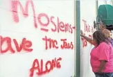  ?? BRIAN BOHANNON, SPECIAL FOR THE COURIER-JOURNAL ?? Whitney Franklin and Liz Herrick pray at a wall vandalized with graffiti at the Louisville Islamic Center on Sept. 17, 2015.