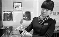  ?? LI XIAOLONG / FOR CHINA DAILY ?? A saleswoman displays a gold ornament at a jewelry shop in Rizhao, Shandong province.