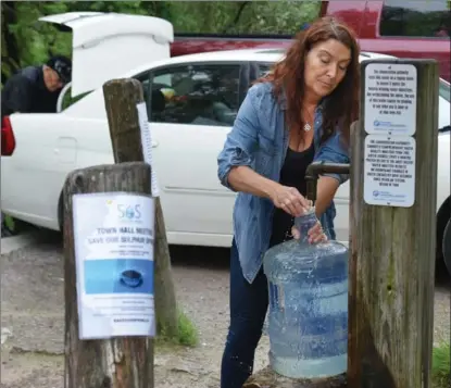  ?? CATHIE COWARD, THE HAMILTON SPECTATOR ?? Joanne Turnell of Save Our Spring fills a bottle with water from the Ancaster artesian well last Thursday afternoon.