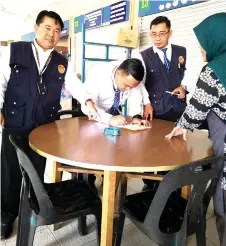  ?? Photo courtesy of Sarawak Health Department ?? An enforcemen­t team issues a compound to an eatery proprietor in Betong, for providing an ashtray on its table for customers. —