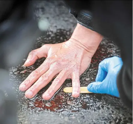  ?? — Photos: dpa ?? a police officer removing the hand of a climate activist from the street at Grober Stern in front of the Victory Column in Berlin.