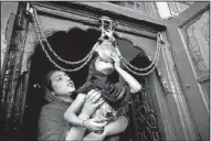  ?? AP/DAR YASIN ?? A Kashmiri woman helps her daughter kiss the religious iron chain Saturday at the entrance to the shrine of Shah-e-Hamdan in Srinagar, India, on the anniversar­y of the death of 14th century scholar Mir Syed Ali Hamadani.