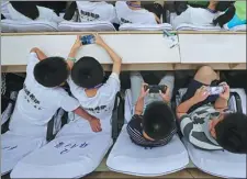  ??  ?? Left: Students play with their smartphone­s during an activity in Zhengzhou, Henan province.
Right: A student in Huaian, Jiangsu province, displays a painting he made that reflects the classroom ban.