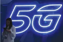  ?? REUTERS ?? A WOMAN looks at her mobile phone next to a 5G sign at the Mobile World Congress in Barcelona, Spain, Feb. 25.