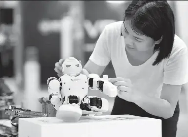  ?? XINHUA ?? A visitor plays with a small robot at a science and cultural innovation exposition held in the China (Fujian) Pilot Free Trade Zone.